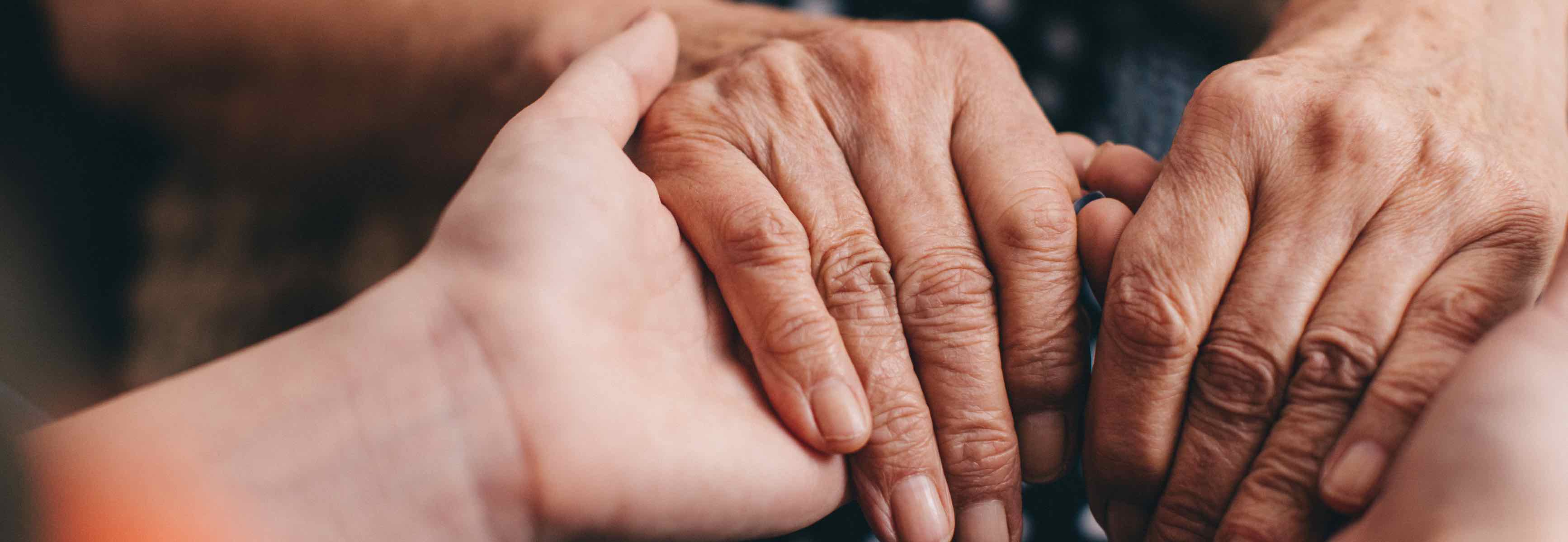Two assisted living residents holding hands.
