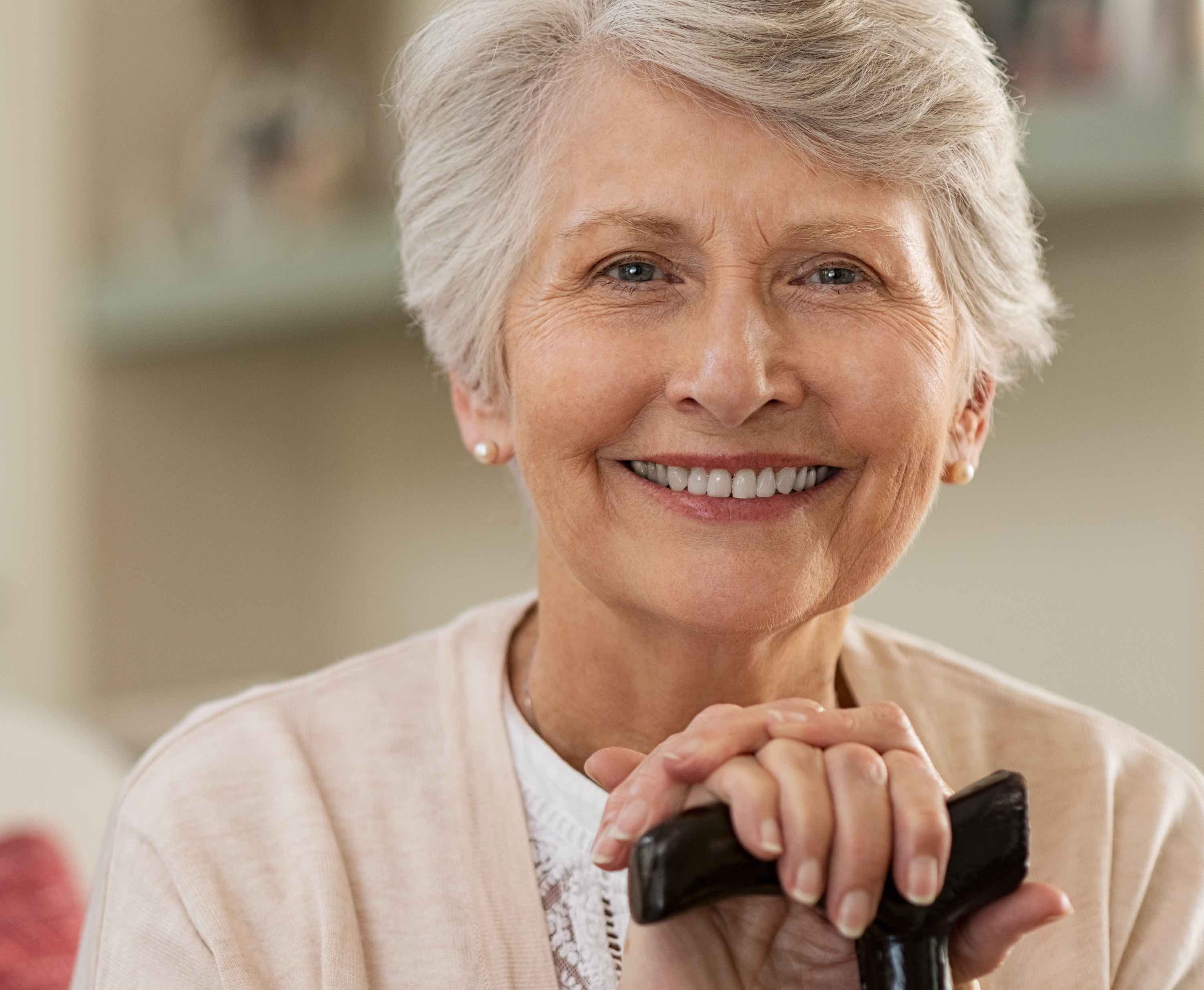 A senior living resident smiling while holding her cane.