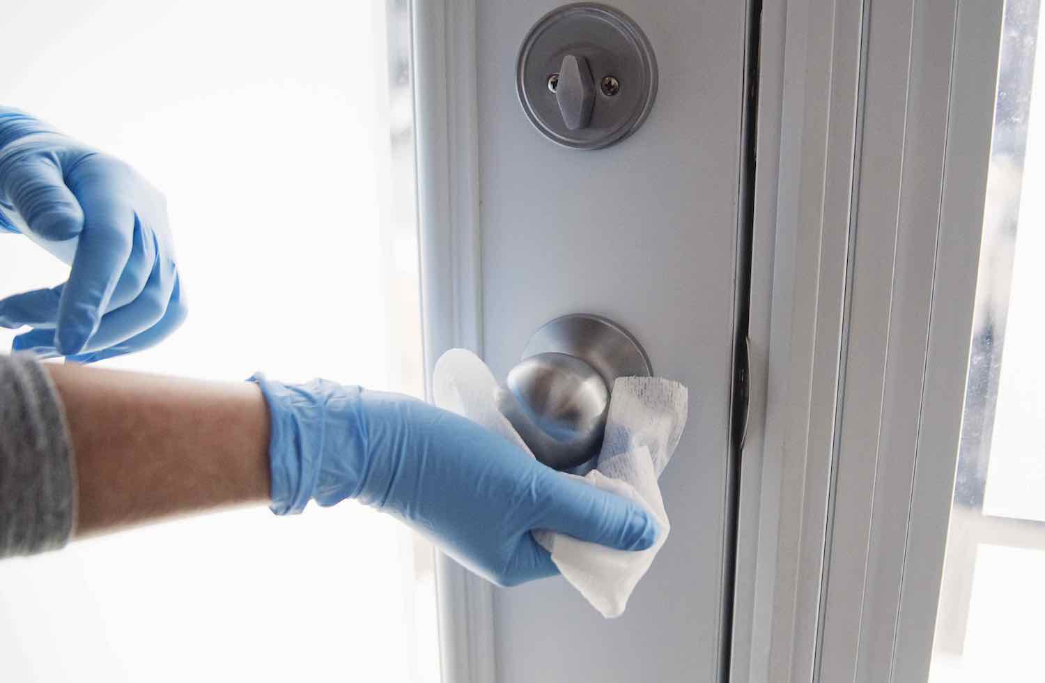 A person sanitizing a doorknob.